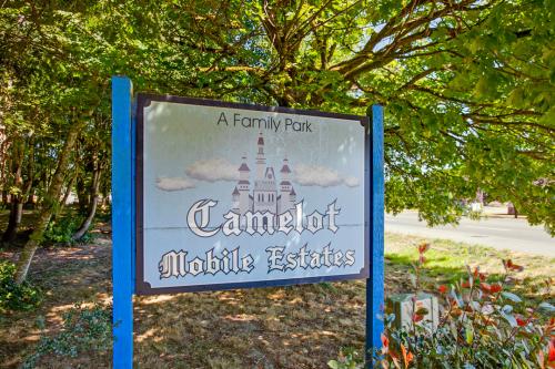 A blue sign with a castle on it reading A Family Park - Camelot Mobile Estates